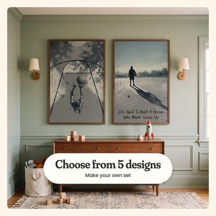 Sage green panelled room with two basketball prints in dark wood frames between two wall lights, above a walnut dresser with wooden blocks and a toy rocket, beside a canvas basket of plush toys and a patterned rug: Vertical Reach and Unbroken Spirit, labeled Choose from 5 designs, Make your own set
