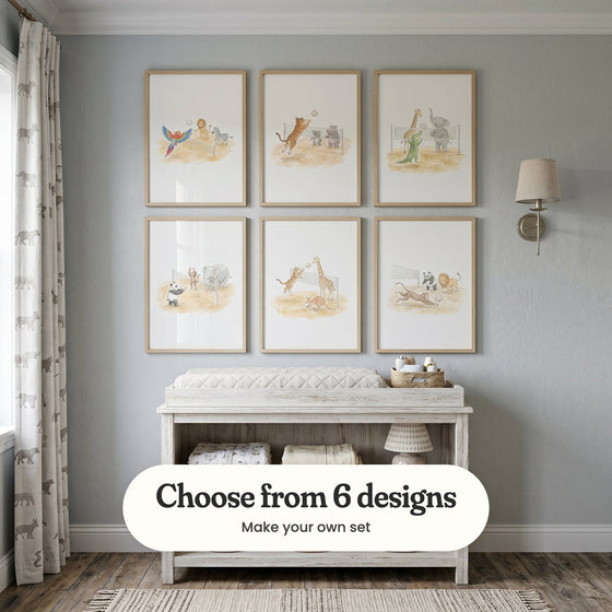 Pale blue grey nursery with six volleyball animal prints in light wood frames in two rows above a whitewashed changing table, beside a wall light and animal print curtains: Safari Sports Match, Wild Volleyball Match, Safari Beach Match, Animal Volleyball Fun, Wild Beach Volley and Beach Volleyball Animals, with a label reading Choose from 6 designs, Make your own set