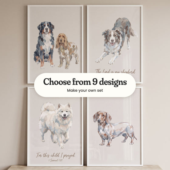 Four beige dog prints in white frames in two rows on a light wood top against a beige wall: a Bernese mountain dog beside a cocker spaniel, a border collie in a playful bow with the words The Lord is my shepherd, a smiling Samoyed with the verse For this child I prayed and a dapple dachshund, with a label reading Choose from 9 designs, Make your own set