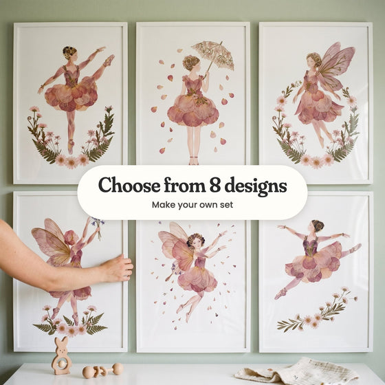 Six fairy and ballerina prints in white frames on a sage wall above a white dresser with a wooden bunny rattle, with someone straightening the lower left frame, with a label reading Choose from 8 designs, Make your own set