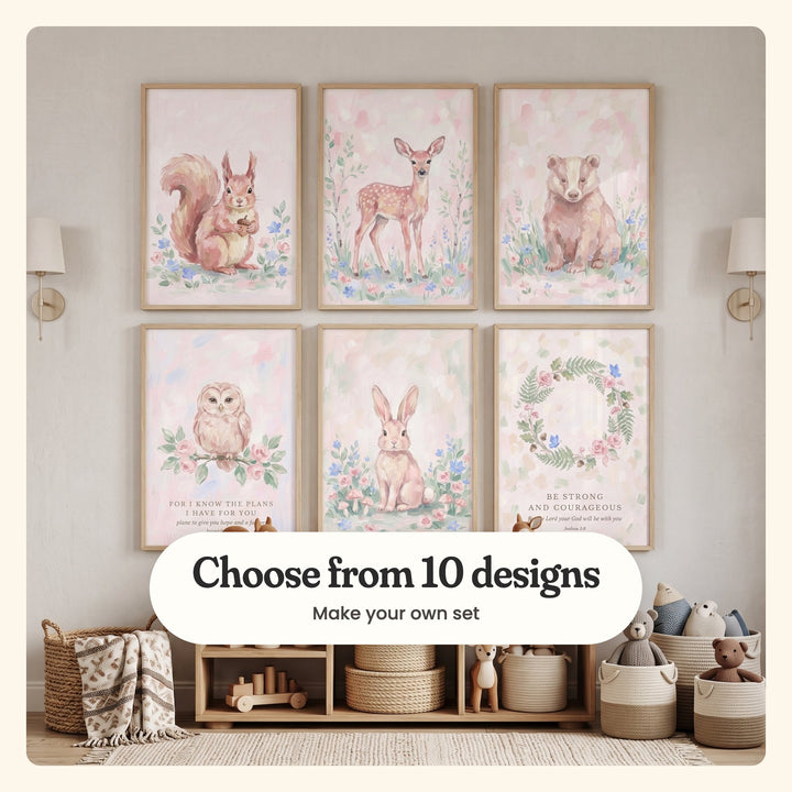 Six blush woodland prints in light wood frames in two rows between two brass wall sconces, above a low wood shelf with a wooden toy train, rope baskets, plush bears and a woven basket with a throw: a squirrel with an acorn, a fawn among birches, a badger, an owl on a rose branch, a bunny among mushrooms and a fern and rose wreath, labeled Choose from 10 designs, Make your own set