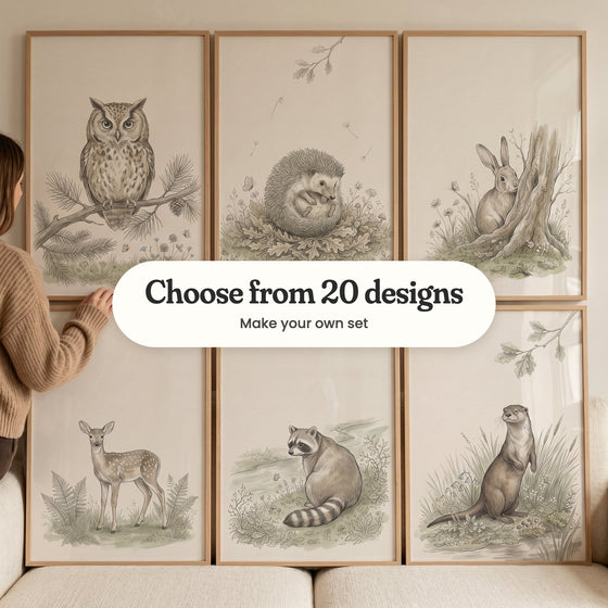 Six sketch-style animal prints in light wood frames in two rows propped on a cream sofa, with a woman in a tan sweater at the left: an owl on a pine branch, a hedgehog curled in oak leaves, a rabbit by a tree stump, a spotted fawn among ferns, a raccoon by a stream and an otter in reeds, with a label reading Choose from 20 designs, Make your own set