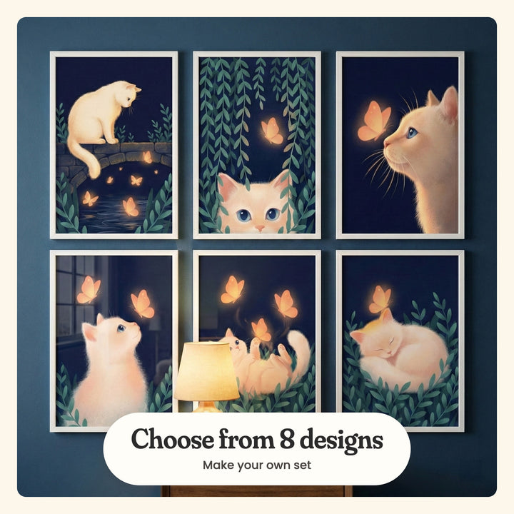 Navy blue wall with six glowing cat prints in white frames in two rows, with a glowing table lamp in front of the lower middle print: Midnight Butterfly Glow, Midnight Gaze, Whiskers And Wings, Glowing Butterfly Dream, Golden Butterfly Glow and Golden Butterfly Dream, labeled Choose from 8 designs, Make your own set