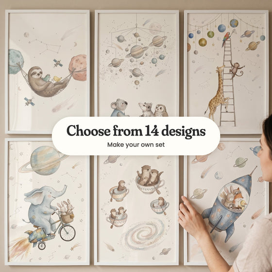 Six space adventure animal prints in white frames on a wall while a woman straightens one, with a label reading Choose from 14 designs, Make your own set