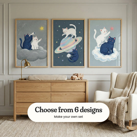 Grey panelled nursery with three cat prints in light wood frames above an oak changing dresser with a brass lamp and a wooden toy truck, beside a cream rocking chair with a knit throw: Celestial Cat Friends, Cosmic Cat Play and Celestial Kittens, with a label reading Choose from 6 designs, Make your own set