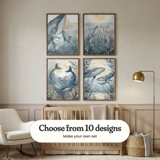 Cream panelled nursery with four whale prints in dark wood frames in two rows above a light wood crib with a knit blanket, beside a brass floor lamp, a cream rocking chair and a woven basket: Gentle Ocean Giants, Celestial Whale Family, Moonlit Whale Family and Ocean Light Voyage, with a label reading Choose from 10 designs, Make your own set