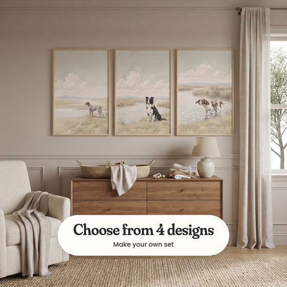 Soft taupe panelled room with three marsh dog prints in light wood frames above a walnut dresser with a woven basket, a folded cloth and a table lamp, beside a cream armchair with a knit throw, a linen curtain and a window: Silent Marsh Sentinel, Loyal River Guardian and Splashing Spaniel, with a label reading Choose from 4 designs, Make your own set