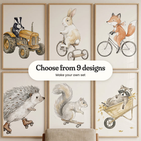 Six woodland animal prints in light wood frames in two rows: a badger driving a mustard tractor, a bunny on a tricycle, a fox in a scarf on a bicycle, a hedgehog in roller skates, a grey squirrel on a skateboard and a raccoon napping in a wheelbarrow of autumn leaves, with a label reading Choose from 9 designs, Make your own set