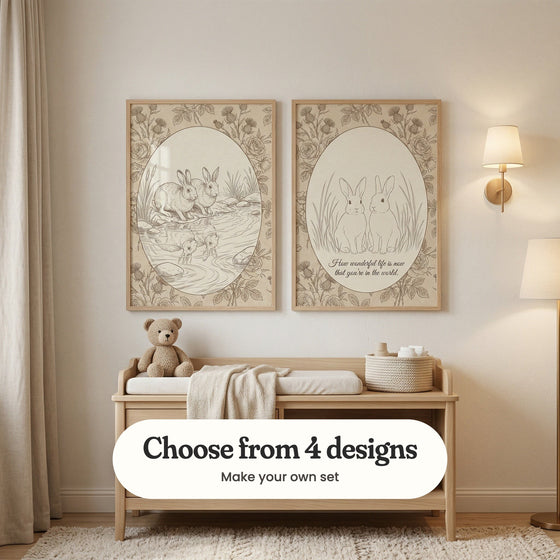 Cream nursery with two bunny prints in light wood frames above a light wood bench with a cushion, a throw, a teddy bear and a woven basket, beside a brass wall lamp, a floor lamp and linen curtains: Reflective Hare Duo and Rustic Bunny Sketch, with a label reading Choose from 4 designs, Make your own set