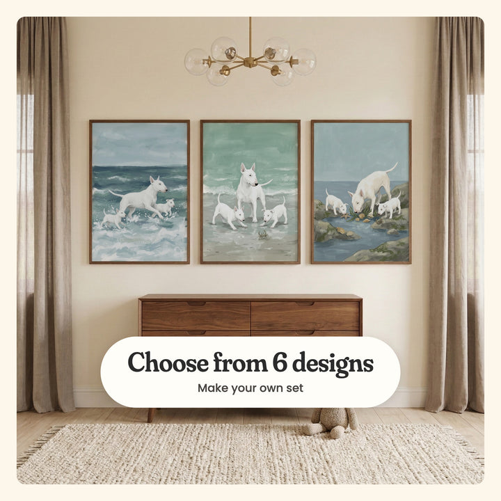 Cream room with three bull terrier prints in dark wood frames above a walnut dresser, under a brass globe light, with a plush toy on a woven rug: Surf And Paws, Seaside Canine Family and Tide Pool Discovery, labeled Choose from 6 designs, Make your own set
