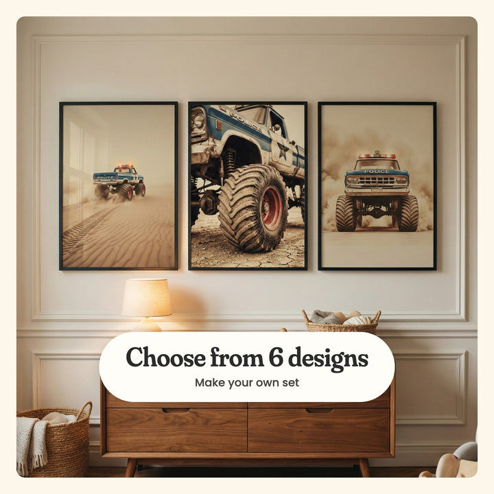 Kids' room with three desert monster truck prints in black frames in a row on a panelled cream wall above a walnut dresser with a table lamp and woven baskets: the truck crossing rippled dunes with its roof lights on, a close-up of its giant muddy tire and the truck head-on through a dust cloud, labeled Choose from 6 designs, Make your own set