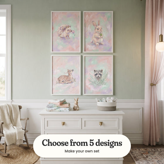 Sage green nursery with four woodland animal prints in white frames in two rows above a white dresser with folded blankets, a small rabbit figure and a basket of plush toys, beside a rocking chair with a knit throw, a pink curtain and a pendant light: Pastel Flower Sniff, Lucky Clover Bunny, Pastel Fawn Dream and Pastel Forest Friend, with a label reading Choose from 5 designs, Make your own set