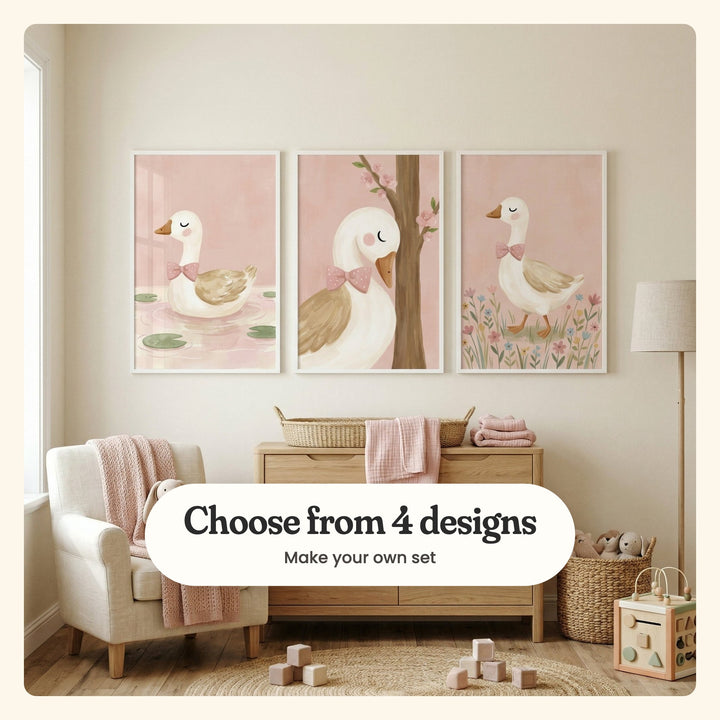 Three goose prints in white frames above a light oak dresser with a woven changing basket and pink muslin, beside a cream armchair with a pink knit throw, a floor lamp and wooden blocks: a goose on a lily pond, a goose resting against a blossom tree and a goose walking through wildflowers, labeled Choose from 4 designs, Make your own set