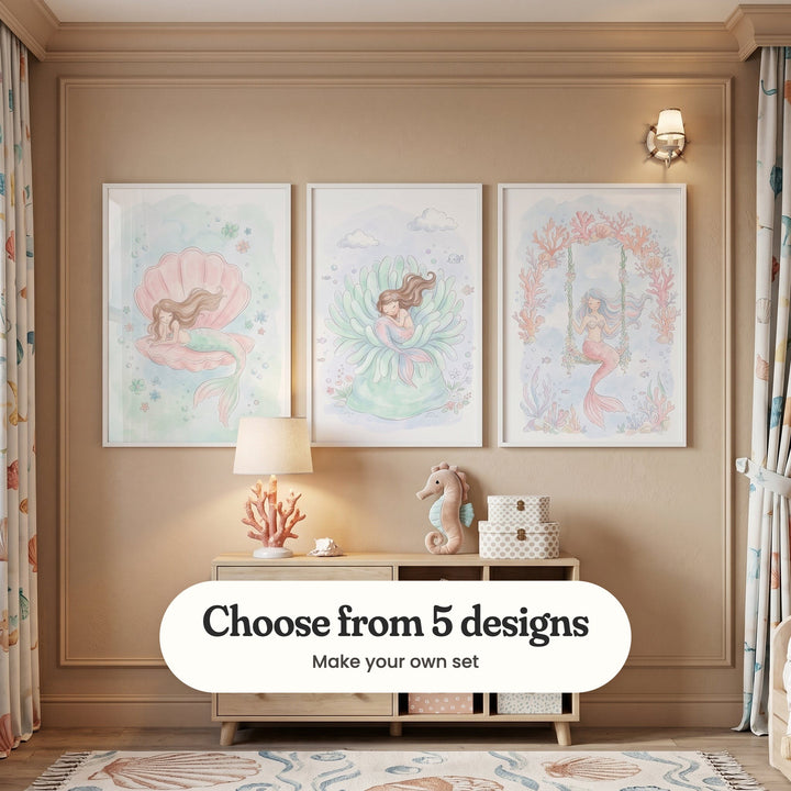 Warm beige panelled room with three mermaid prints in white frames above a light wood sideboard with a coral table lamp, a small shell, a plush seahorse and polka dot boxes, beside a wall light, sea print curtains and a shell patterned rug: Seashell Dreams, Serene Sea Slumber and Pastel Mermaid Swing, with a label reading Choose from 5 designs, Make your own set