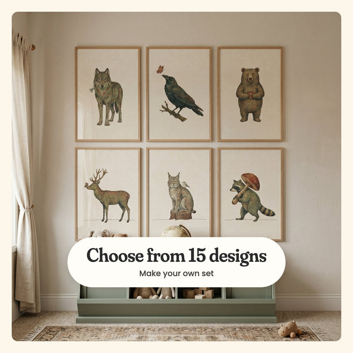 Kids' room with six woodland prints in light wood frames above a sage green toy bench with plush toys: a wolf with a blue flower, a raven, a bear holding a mug, a buck with a butterfly, a lynx on a stump and a raccoon with a mushroom, labeled Choose from 15 designs, Make your own set