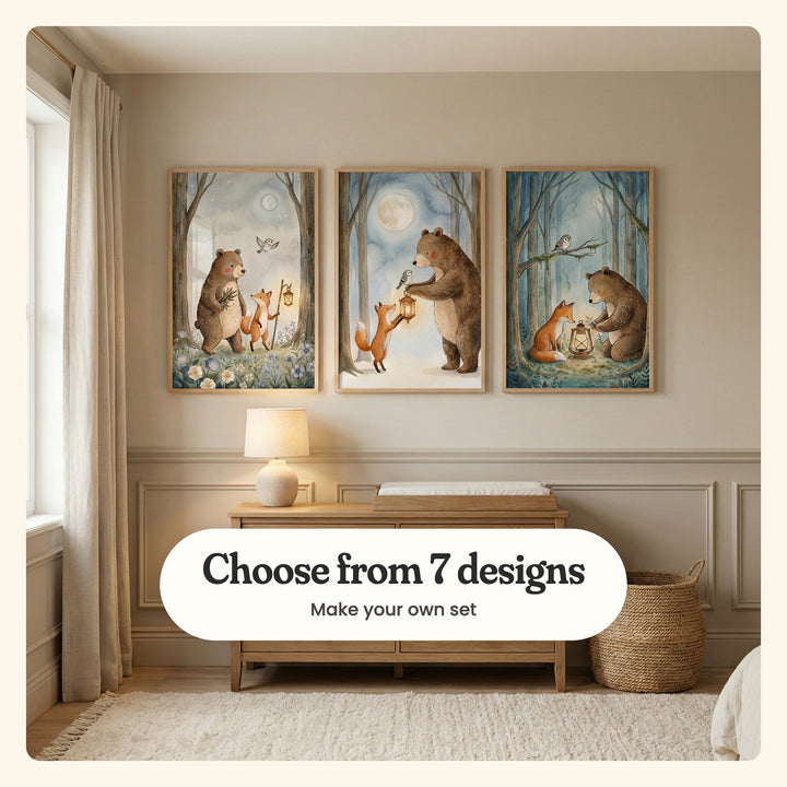 Three bear and fox prints in light wood frames on a panelled wall above a light wood dresser with a changing pad and a ceramic lamp, beside linen curtains and a woven basket on a shaggy cream rug: the bear carrying sticks beside the fox with a lantern, the bear handing the fox a lantern under a full moon and the pair by a lantern in a misty blue forest, labeled Choose from 7 designs, Make your own set