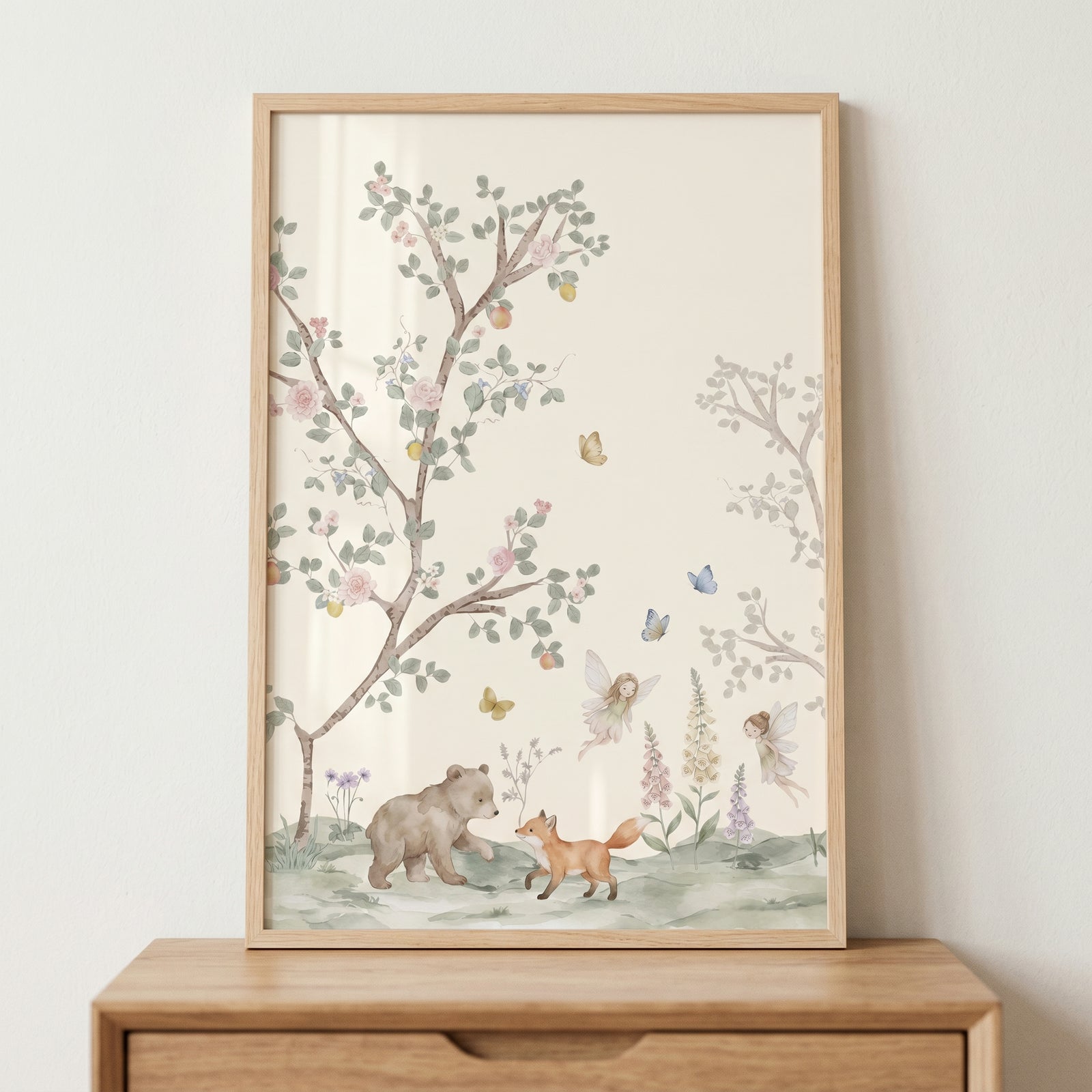 Watercolor walking bear and fox wall art with fairies and trees in a wood frame resting on a wooden dresser.