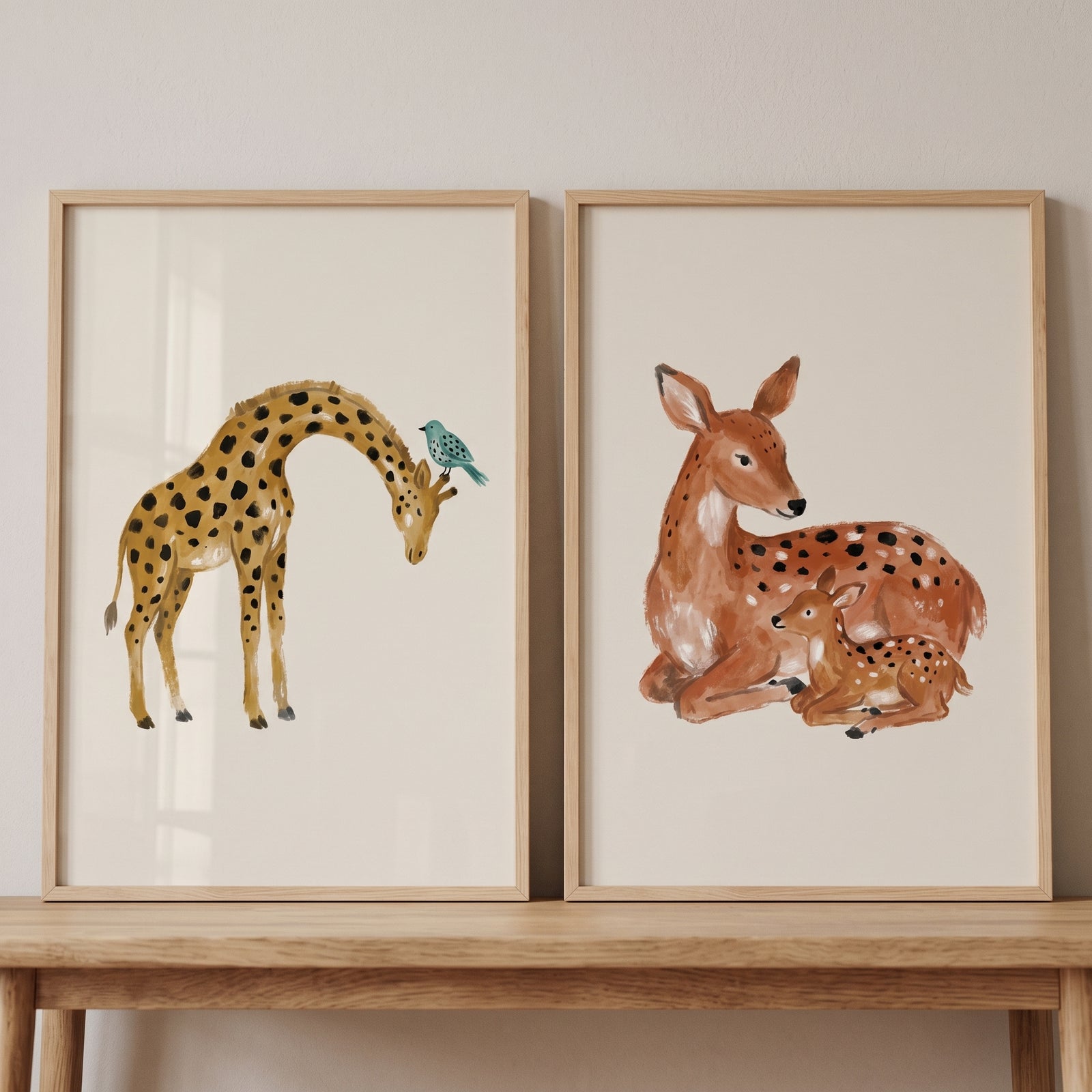 Warm earthy watercolor animal wall art set of 2 featuring a giraffe with a bird and a mother deer with her fawn.