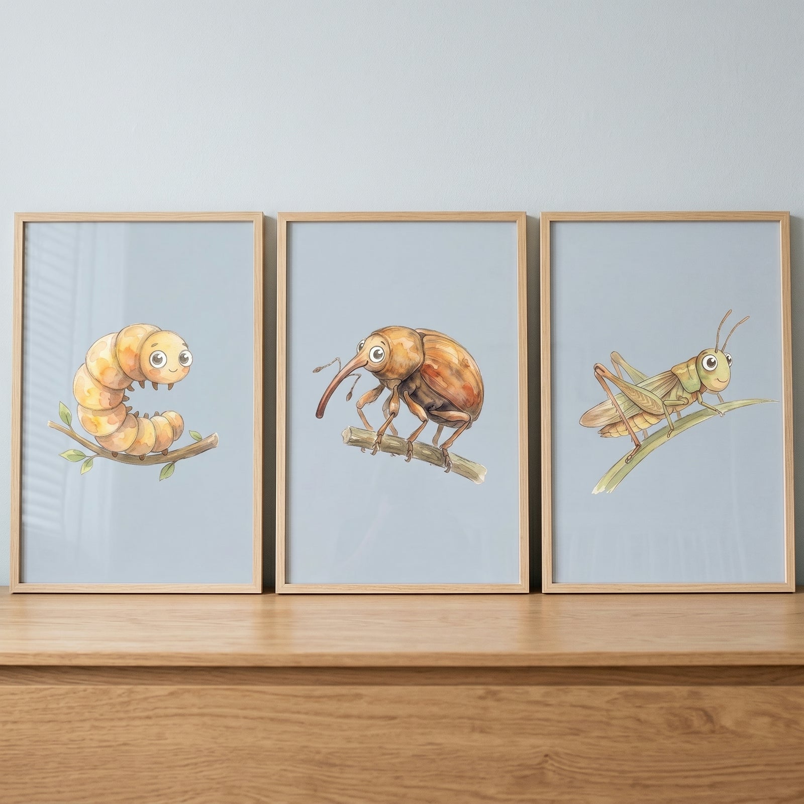 Warm tone bug wall art set of 3 featuring a caterpillar, weevil, and grasshopper in wood frames on a tabletop.