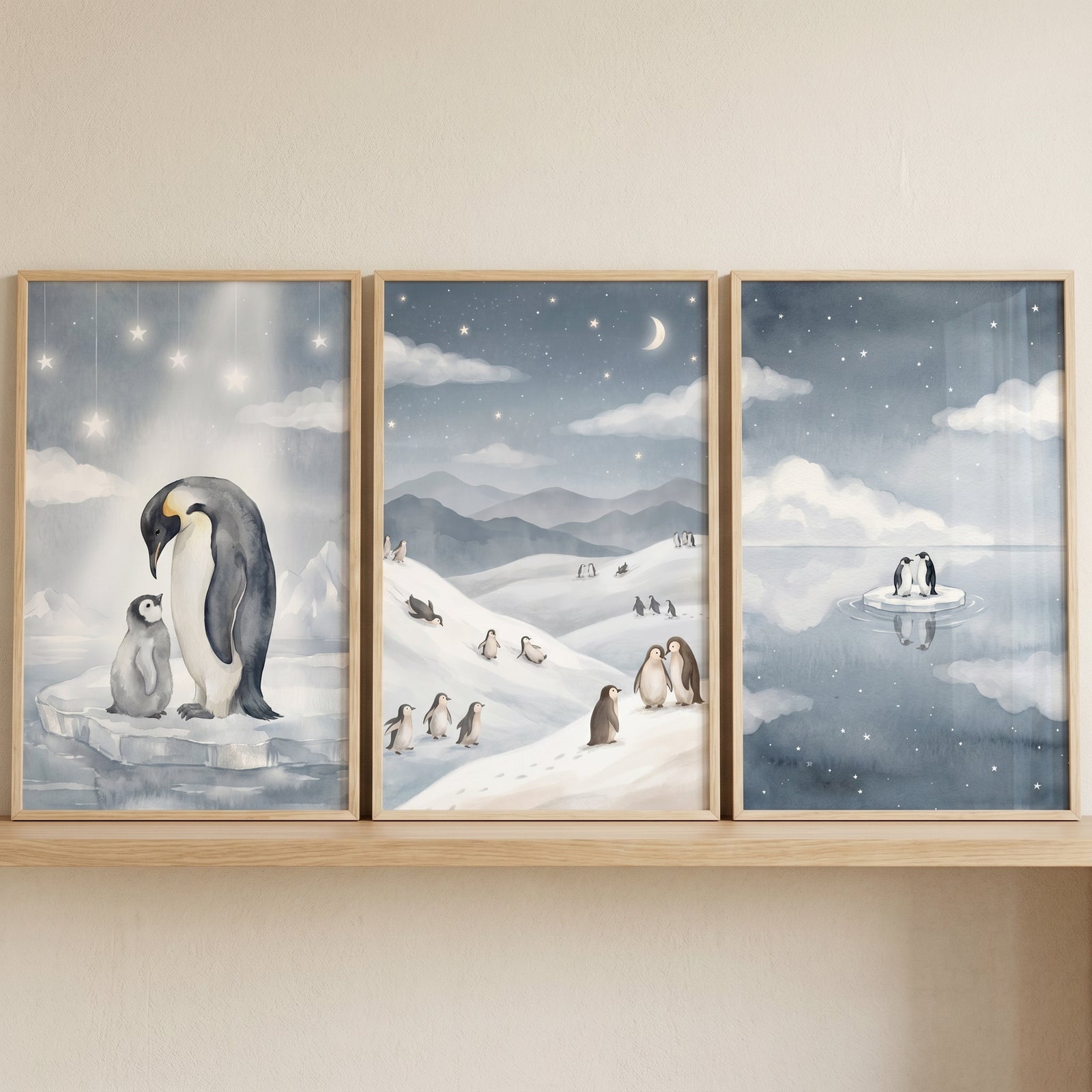 Watercolor arctic blue penguin wall art set of 3 with penguins on snow and ice floes under a starry night sky and moon.