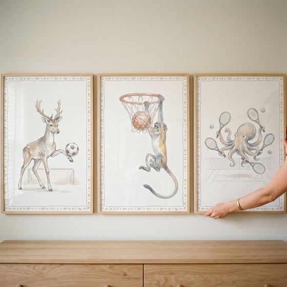 Deer, monkey, and octopus illustrations in a watercolor athletic sports animals wall art set of 3 above a dresser.