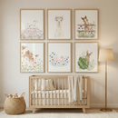 A serene nursery scene featuring a light-toned wooden crib centered under six framed illustrations on a neutral wall. The art depicts various baby farm animals in a soft watercolor style: a lamb, an alpaca with a flower crown, a horse behind a fence, a brown and white calf, a pink piglet among blue flowers, and a rabbit behind a large green leaf. To the left of the crib is a woven basket filled with toys, and to the right stands a minimalist floor lamp with a gold base and a cream-colored shade.