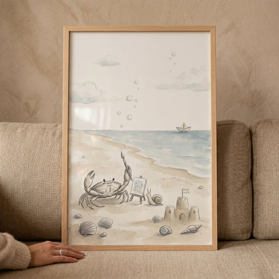 Watercolor beach artist crab wall art shows a crab at an easel, a sandcastle, and a snail on a sandy shore.