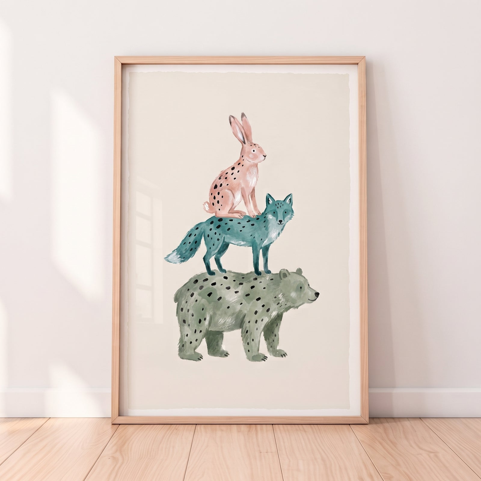 Spotted pink rabbit, blue fox, and green bear stacked in watercolor bear fox rabbit wall art in a light wood frame.