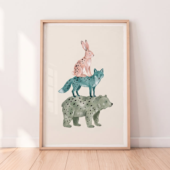 Spotted pink rabbit, blue fox, and green bear stacked in watercolor bear fox rabbit wall art in a light wood frame.