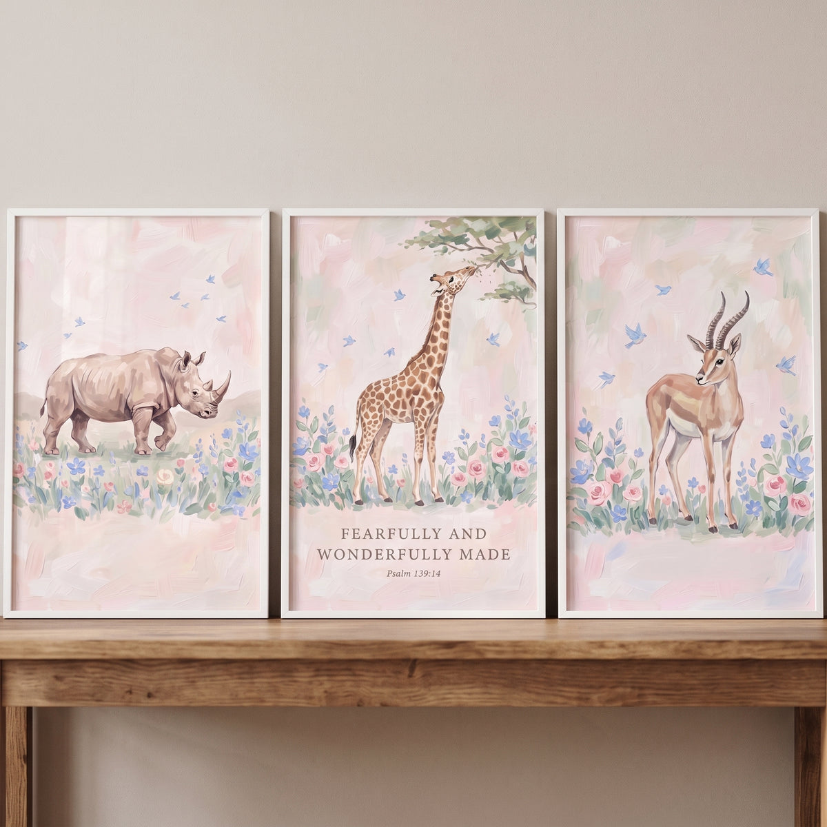 Watercolor bluebird safari animals wall art set of 3 with a rhino, giraffe, and gazelle above a wooden table.