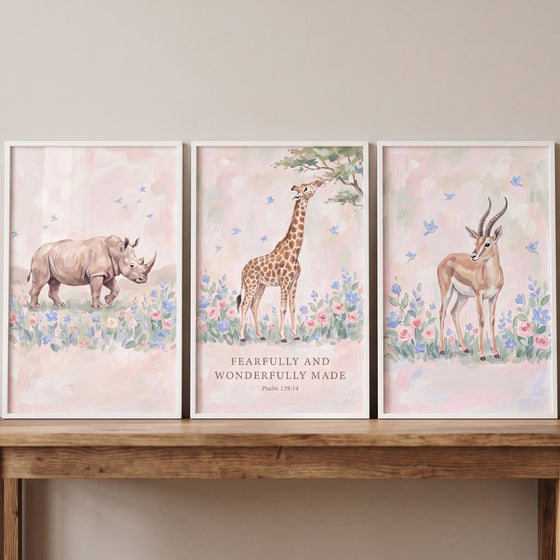 Watercolor bluebird safari animals wall art set of 3 with a rhino, giraffe, and gazelle above a wooden table.