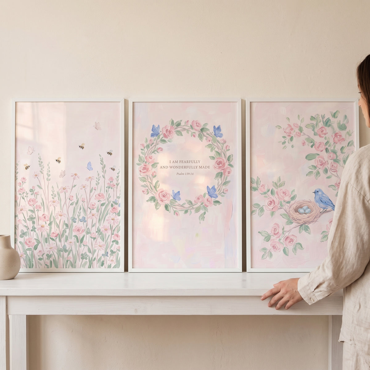 Watercolor blush botanical floral wall art set of 3 with pink flowers, a bird, and scripture on a table.