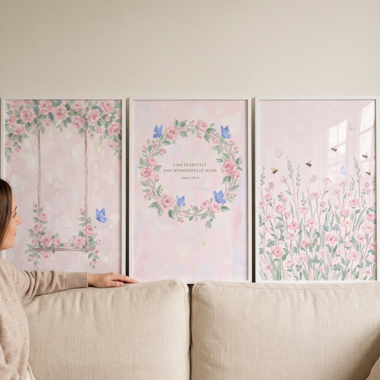 Watercolor botanical pink rose floral wall art set of 3 featuring a swing, a wreath, and meadow scenes above a couch.