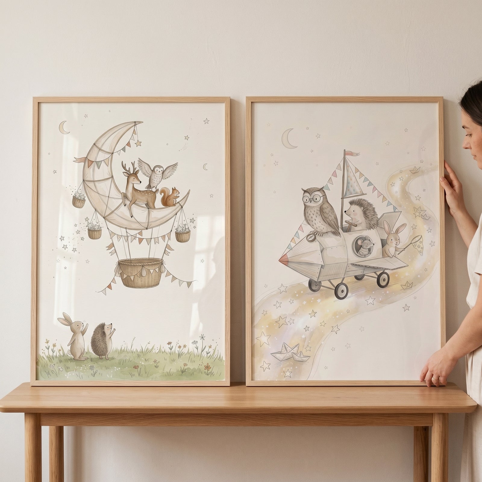 A person holds a watercolor celestial forest animals wall art set of 2 featuring woodland animals in fantasy vehicles.