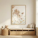 A light-colored nursery or playroom features a large, framed watercolor-style illustration of a brown and white calf sniffing yellow flowers. The artwork is centered on a neutral-toned wall above a light wood storage bench. The bench has four drawers and is topped with light beige cushions and two matching throw pillows. 