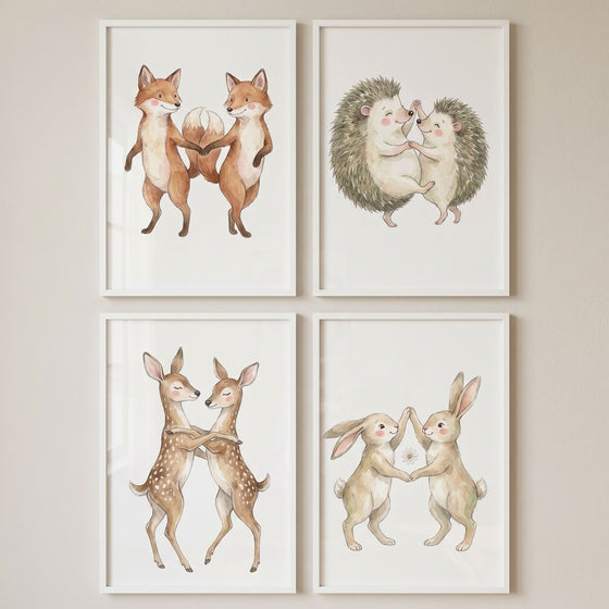 Watercolor dancing woodland animal wall art set of 4 with pairs of foxes, hedgehogs, deer and rabbits in white frames.