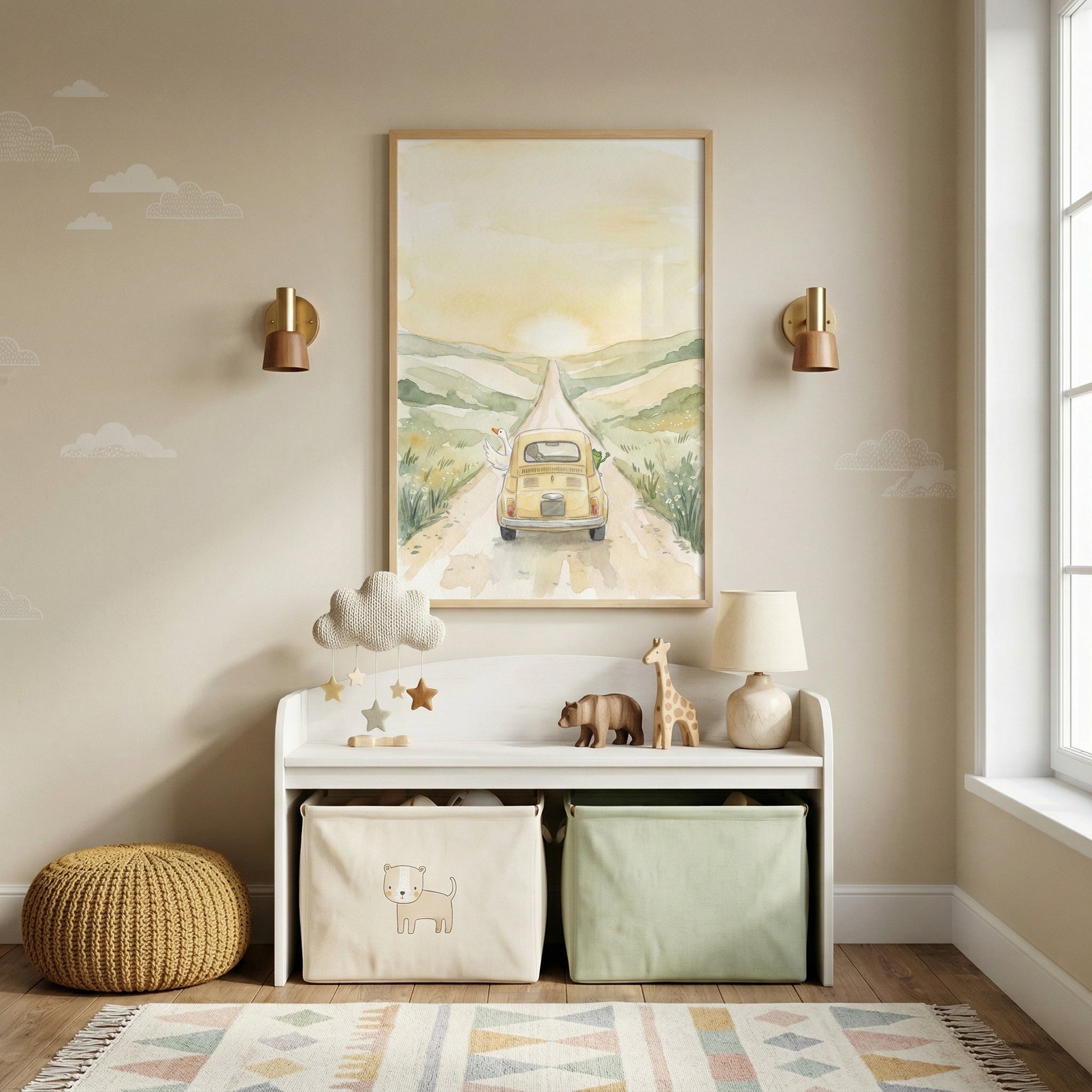 A cozy, neutral-toned nursery or playroom features a central piece of framed wall art depicting a soft, watercolor-style landscape. In the illustration, a vintage-style yellow car travels along a winding dirt path through green hills, heading toward a glowing sun on the horizon. The wall is a warm beige, accented with delicate white cloud decals and flanked by two modern gold and brown wall sconces.
