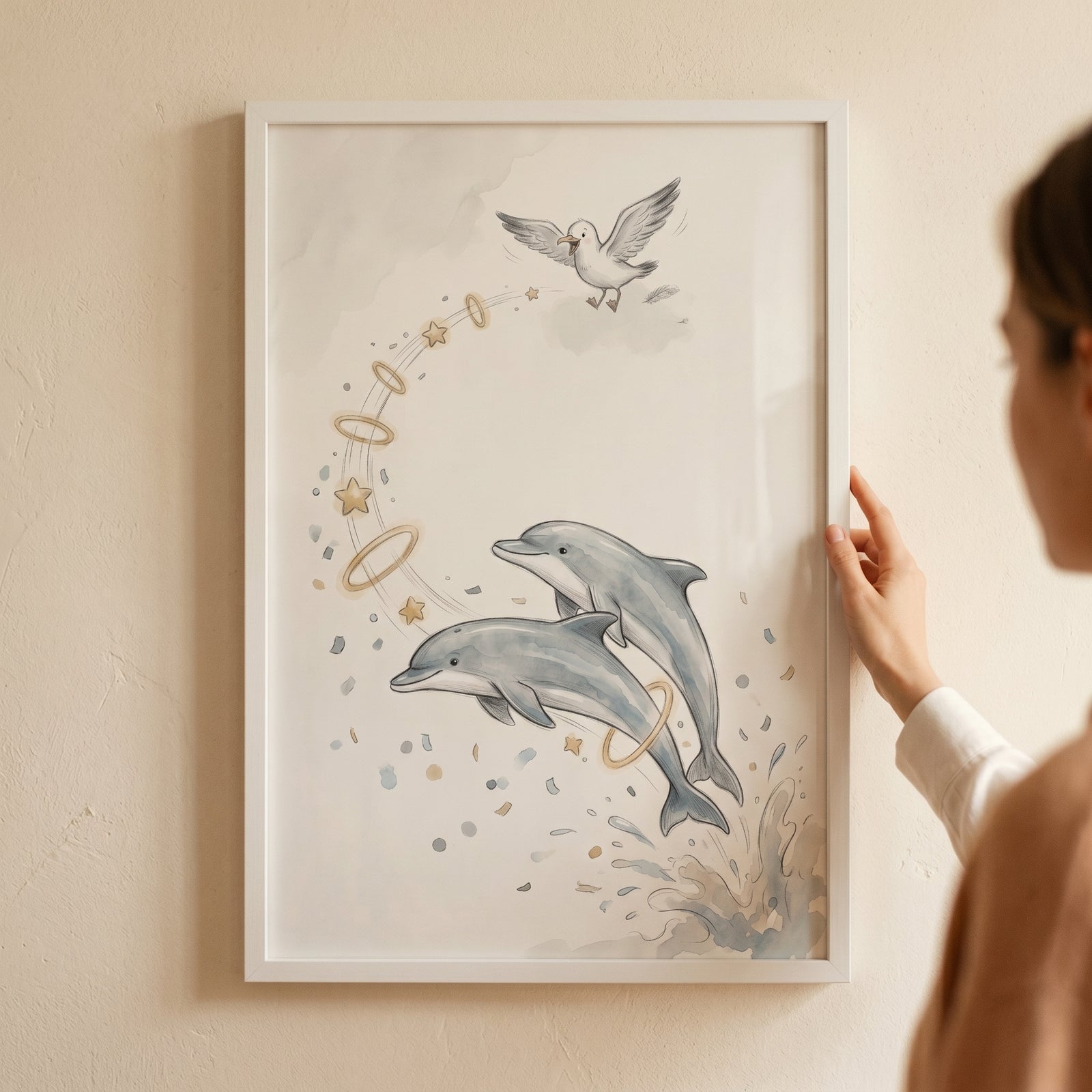 Two dolphins leap through golden rings and stars in this watercolor ethereal jumping dolphin wall art with a seagull.