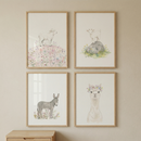 Four framed watercolor prints show a lamb standing in soft wildflowers a baby goat on a rock a small donkey in a meadow and a llama wearing a delicate flower crown. The gentle pastel tones and sweet farm animals create a calm whimsical nursery wall display.