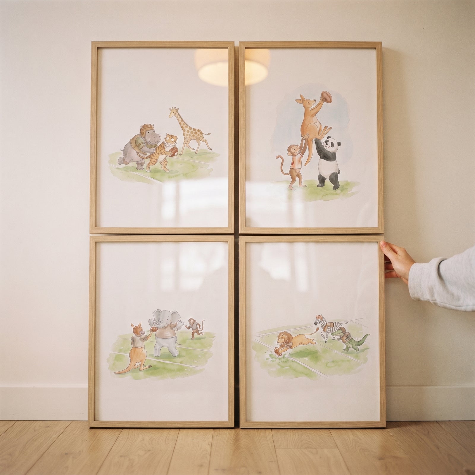 Watercolor football safari animals wall art set of 4 shows wild animals playing sports on a grassy field.