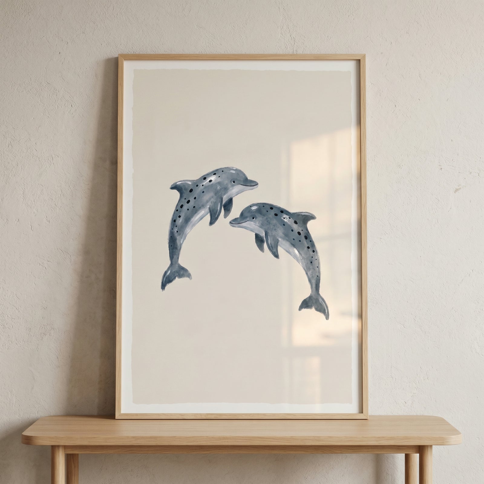 Watercolor grey leaping dolphin wall art with two spotted dolphins on a beige background in a light wood frame.