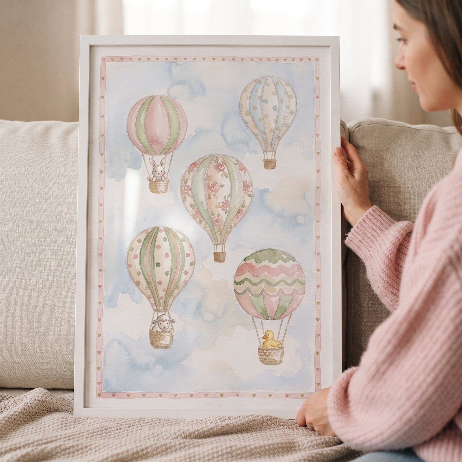Framed watercolor hot air balloon wall art featuring pastel balloons and small animals in a soft blue sky.