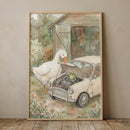 A framed watercolor-style illustration depicts a whimsical and charming scene in a rustic garden. In the center, a large white goose and a small green frog are busily repairing a tiny, cream-colored vintage compact car. 