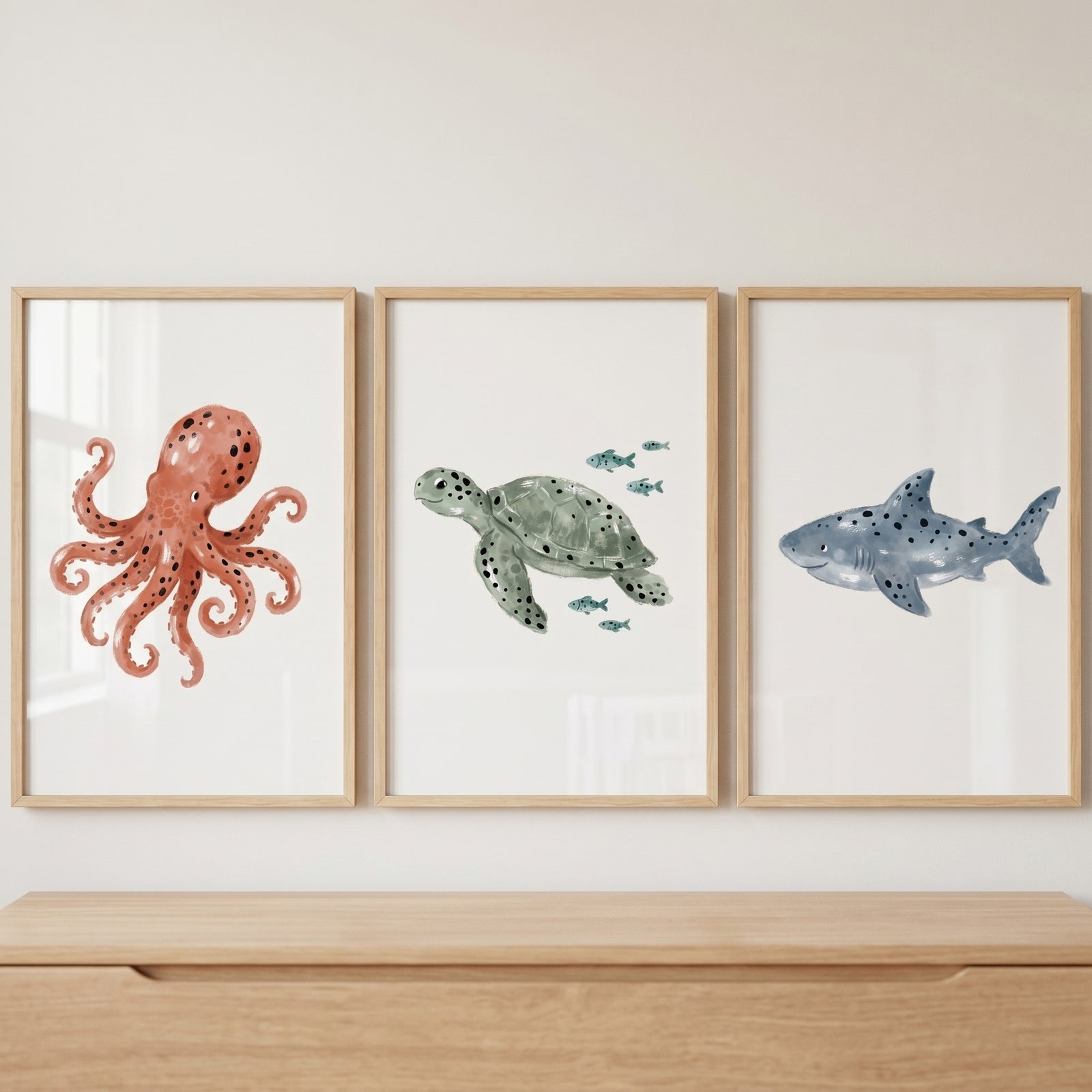 Watercolor muted sea creature wall art set of 3 featuring a red octopus, green sea turtle, and blue shark in wood frames.