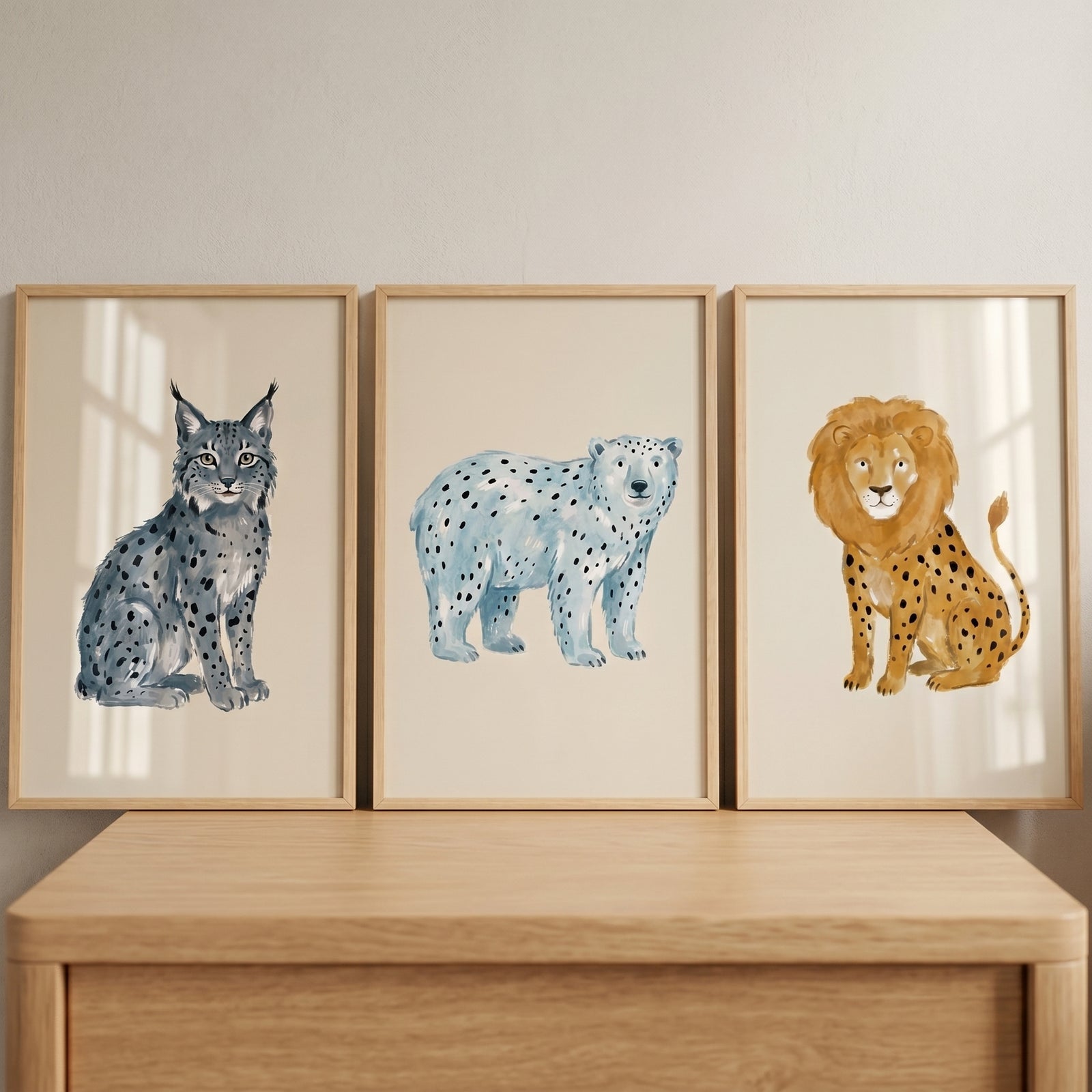 Watercolor neutral spotted animals wall art set of 3 with a lynx, polar bear, and lion in frames on a dresser.