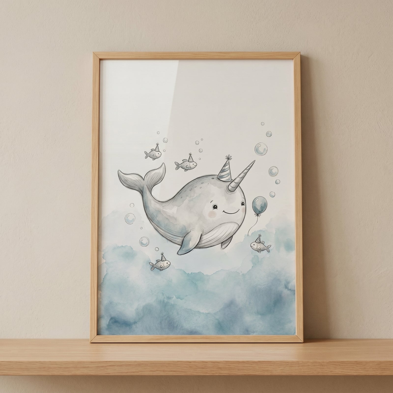 Framed watercolor party hat narwhal wall art with a smiling narwhal, tiny fish, and bubbles above a soft blue sea.