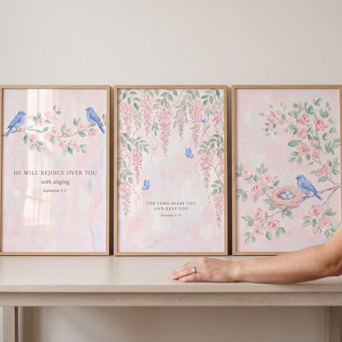Watercolor pink blossom bird wall art set of 3 featuring Bible verses in wooden frames on a table.