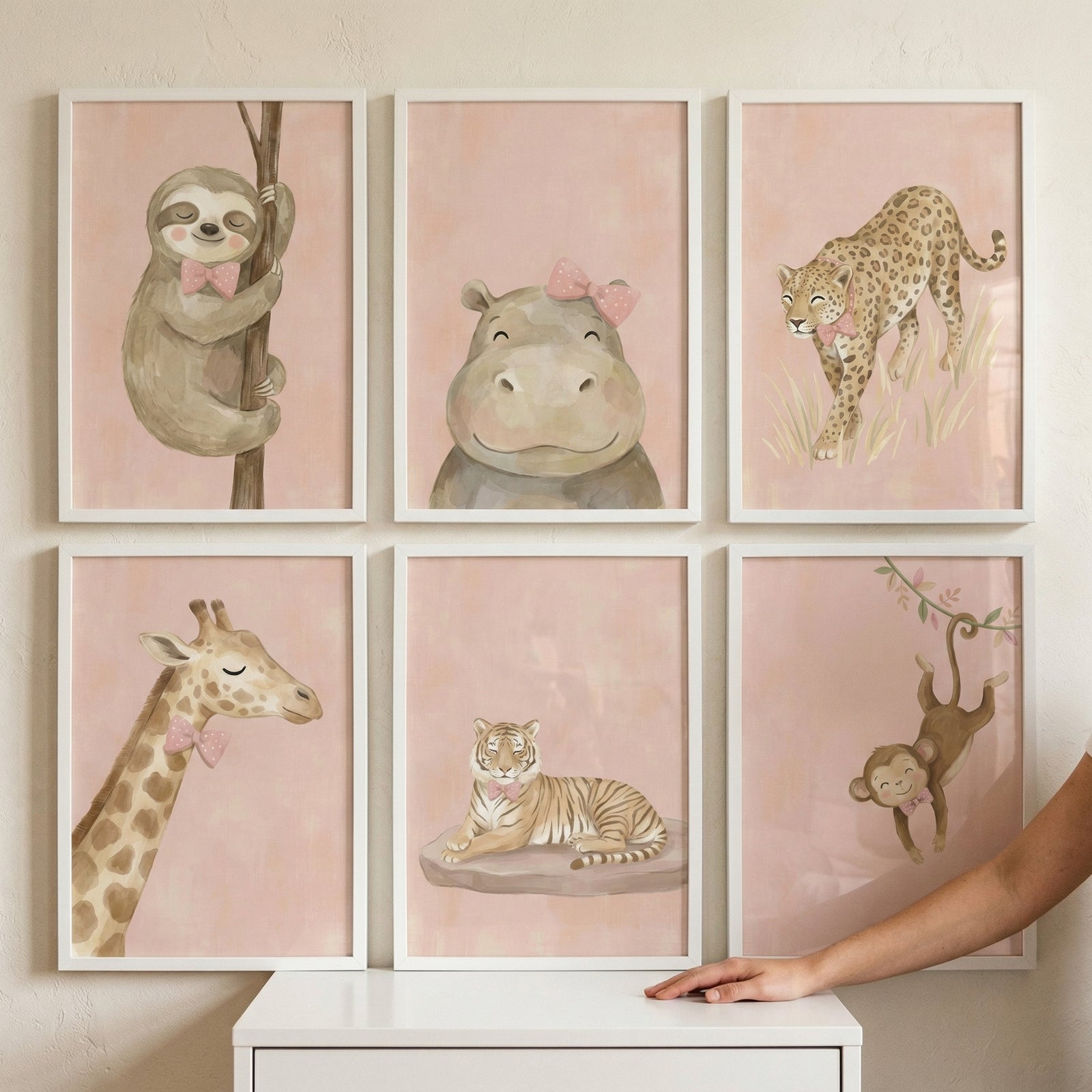 This set of six framed nursery art prints features a collection of charming jungle animals, each rendered in a soft watercolor style. The illustrations include a sloth hanging from a branch, a smiling hippopotamus, a graceful leopard, a long-necked giraffe, a resting tiger, and a playful monkey swinging from a vine. 
