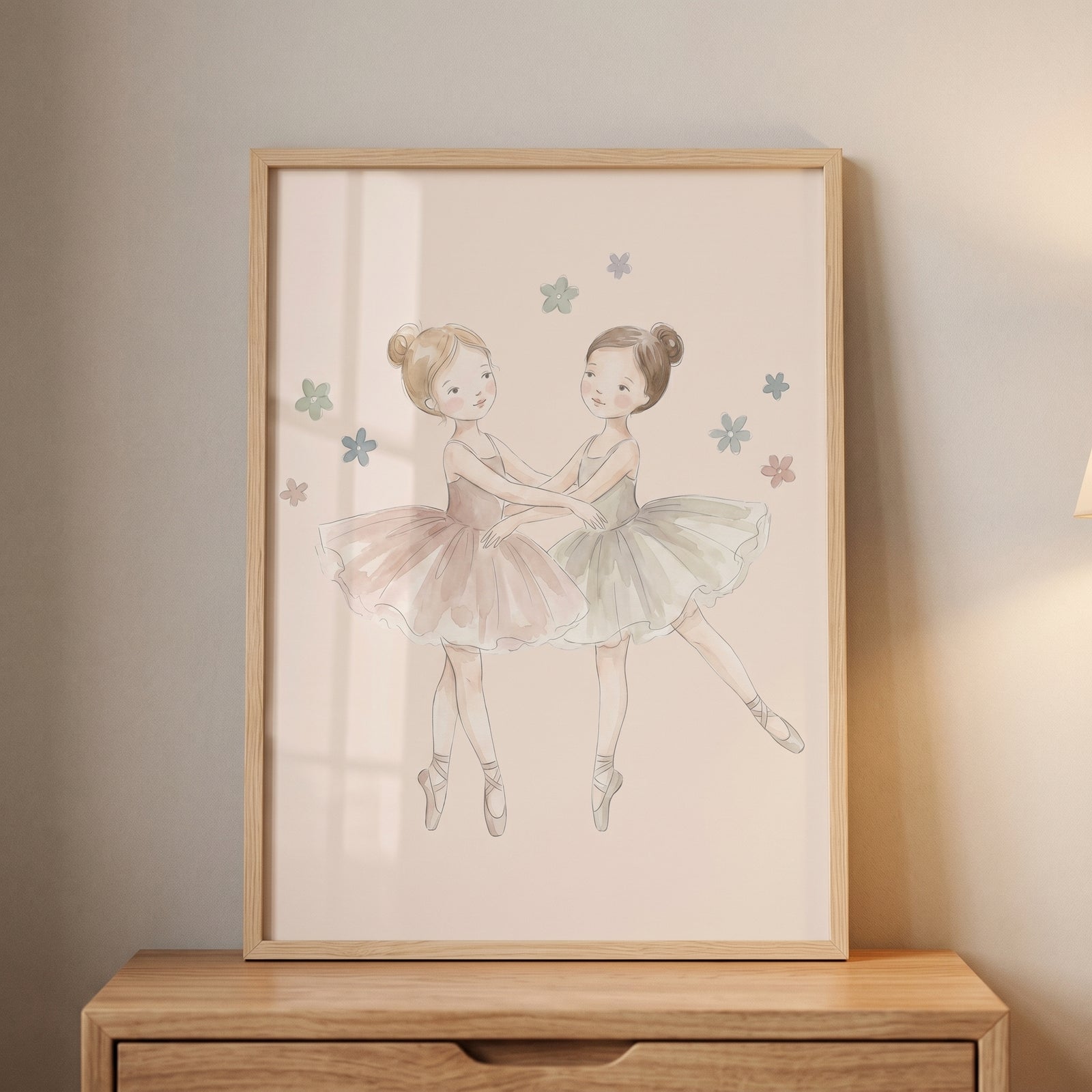 Framed watercolor pink tutu ballerina wall art on a wooden dresser, depicting two young girls dancing in soft tutus.
