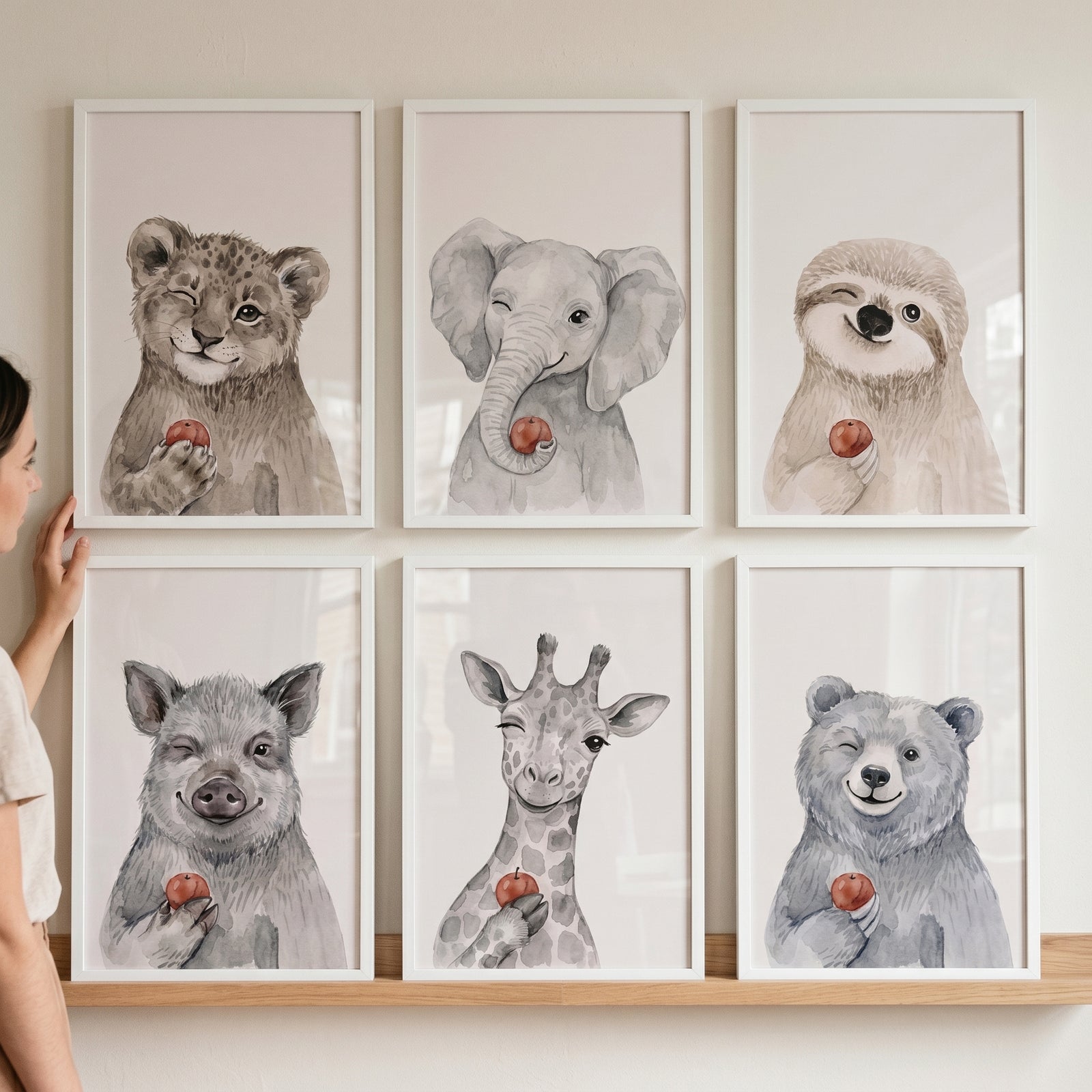 Watercolor red apple animals wall art set of 6 prints showing a lion, elephant, sloth, pig, giraffe, and bear on a wall.